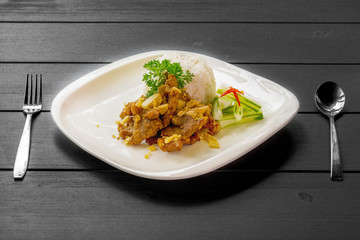 fired pork with garlic on steam rice on black table