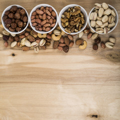 Four bowls with nuts on a  wooden table.