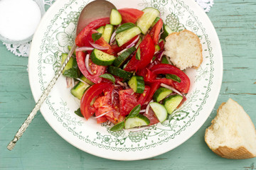 A refreshing classic summer salad often found at cookouts and picnics is made with tomatoes, cucumber, onion and basil. Selective focus was used on this image.