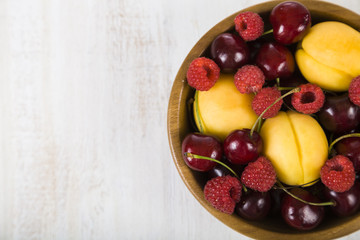 Ripe berries in a plate on a wooden table.