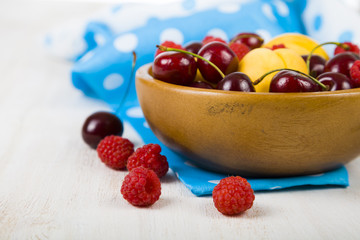 Ripe berries in a plate on a wooden table.