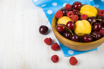Ripe berries in a plate on a wooden table.