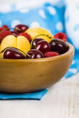 Ripe berries in a plate on a wooden table.