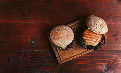 A real burger on a wooden background. With a large and juicy cutlet tender cheese sauce and mustard. Rustic