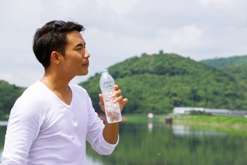 One Asian man is drinking a bottle of water with nature background