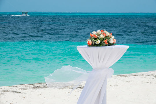 Bukiet ślubny na białym stojaku na plaży nad turkusowym morzem karaibskim w Meksyku