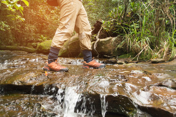 foot of hiking man stand on waterfall in forest.