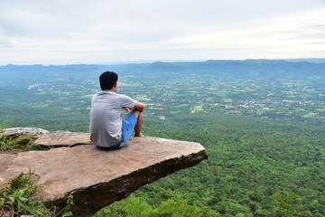 Fototapeta na wymiar a man sitting on cliff at Pha Hum Hod, Sai Thong National Park, Chaiyaphum Province, Thailand.