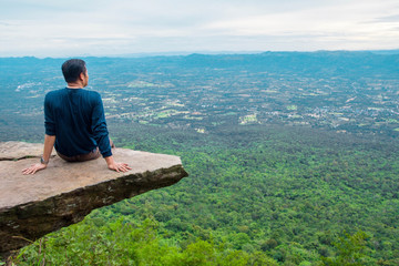 Naklejka na ściany i meble a man sitting on cliff at Pha Hum Hod, Sai Thong National Park, Chaiyaphum Province, Thailand.