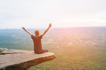 a woman sitting on cliff at Pha Hum Hod, Sai Thong National Park, Chaiyaphum Province, Thailand.