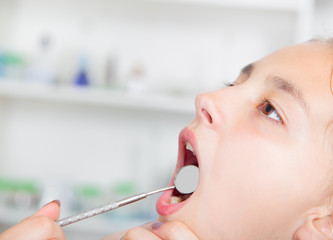 Close-up of little girl opening his mouth wide during treating her teeth by the dentist