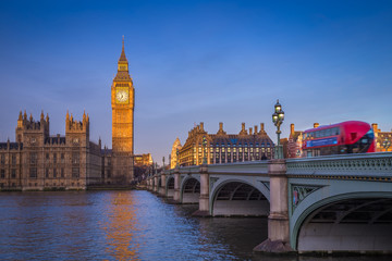 Fototapeta na wymiar London, England - The iconic Big Ben with Houses of Parliament and traditional red double decker bus on Westminster Bridge at sunrise with clear blue sky