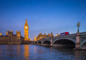 Fototapeta na wymiar London, England - The iconic Big Ben with Houses of Parliament and traditional red double decker bus on Westminster Bridge at sunrise with clear blue sky