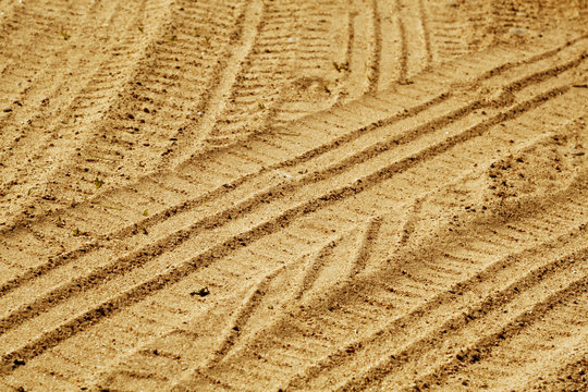 Tire imprints on sandy desert road.