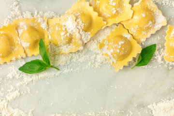 Overhead photo of ravioli with flour and basil leaves