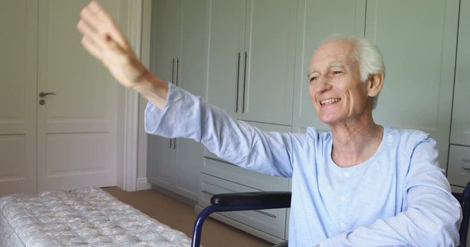 Senior man in wheelchair waving at home