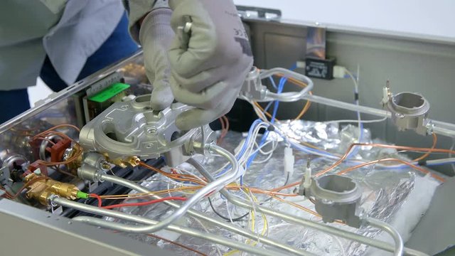 A man is using a rench to fix a problem inside the stove. The device was ot working properly. 