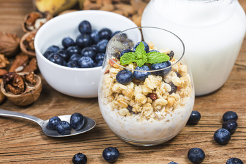 Healthy breakfast: oat granola with yogurt and fresh blueberries on wooden background