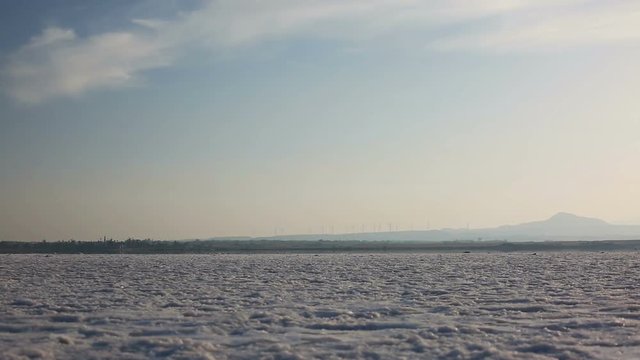 Dry salt lake with a windmill farm on the background at sunset