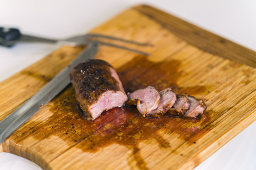 Top view of a wooden serving board with roasted duck breasts