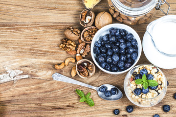 Healthy breakfast: oat granola with yogurt and fresh blueberries on wooden background