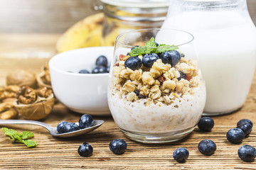 Healthy breakfast: oat granola with yogurt and fresh blueberries on wooden background