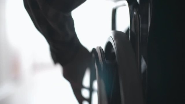 Tracking with close up of silhouette of male hand turning wheels of wheelchair
