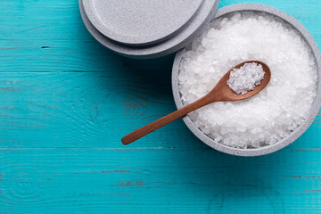 Sea salt in an stone bowl with small wooden spoon on a blue wooden table