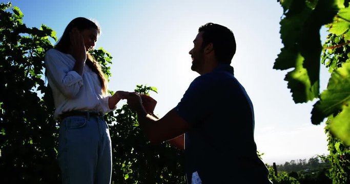 Man putting engagement ring on womans hand in vineyard