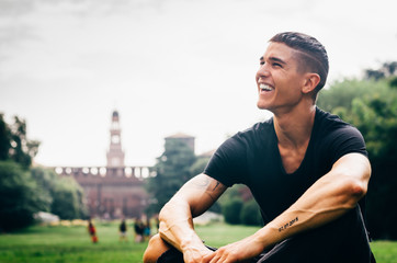 Young handsome man laughing (20-25) with Milan, Italy background
