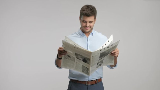Young guy reading a newspaper and smiling