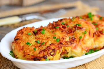 Fried potato cutlets with ham and green onions on a white plate. Simple potato cutlets recipe. Rustic style. Closeup