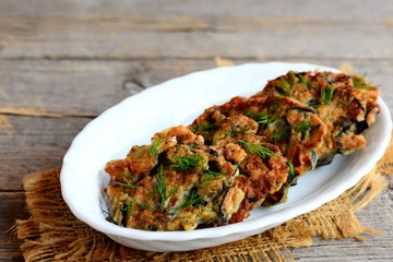 Fried eggplant cutlets with garlic and dill on a white plate and a vintage wooden background. Delicious summer vegetarian recipe. Closeup