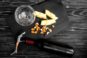 bottle of red wine, appetizers and corkscrew on wooden backgroun