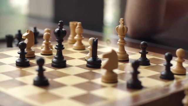 Close-up of the hand of a man playing chess. Close-up of man who is making move in chess game. Man and woman playing chess in a cafe.