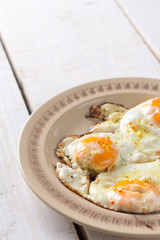Homemade fried eggs on the plate above wooden table
