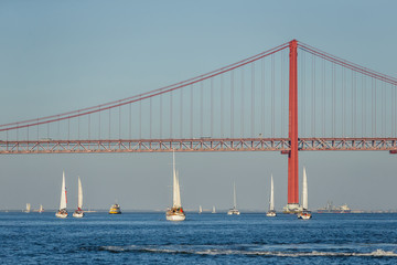 Boats sailing in river Tagus with bridge in Lisbon, Portugal