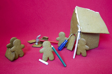 Gingerbread men making house on red
