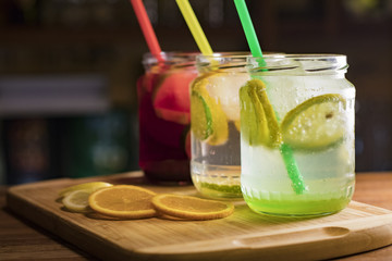Three glasses of different flavored lemonades on the counter served in jars