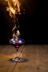 Glass of flaming cocktail with sparks of buring cinnamon (flaming lamborghini)