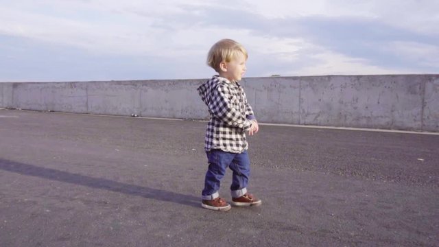 A little 2 year old baby boy is walking on sunset. Child make his first steps outdoor