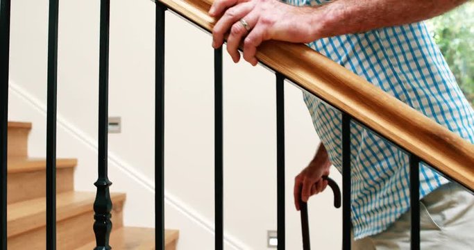 Senior man climbing upstairs with walking stick