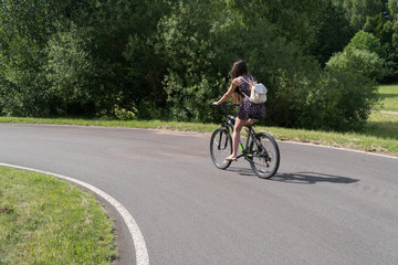 Girl riding a bicycle. Side view. Forest and clouds in the background