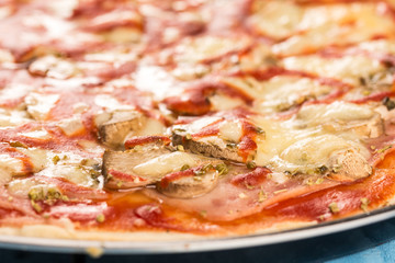 Closeup macro fresh baked round pizza with cheese ham tomato sauce mushrooms