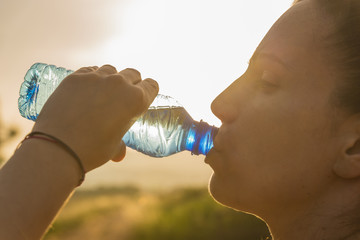 Girl drinking water at sunset.