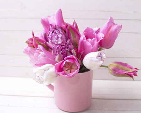 Bright pink  spring tulips flowers in pink  cup on white  wooden background.
