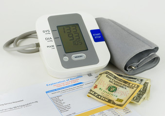 A personal blood pressure and heart rate meter on light background with explanation of benefits and US cash. The display indicates elevated blood pressure. Good image for health care costs