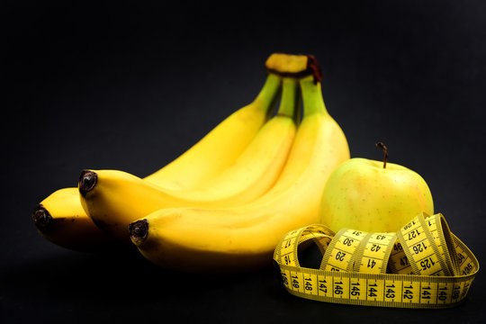 Bananas and green apple near measuring tape