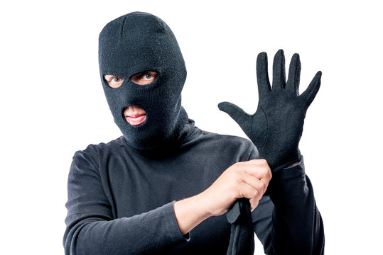 Portrait of a robber in a mask on his face straightens a glove on a white background