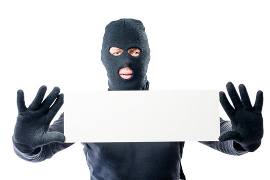 Robber in black clothes and mask with a poster in hands on a white background
